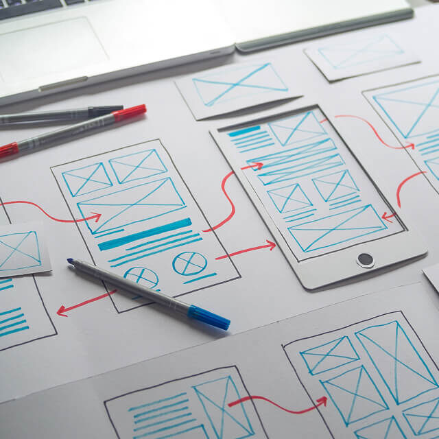 A hand drawn UI flow laid out on a desk